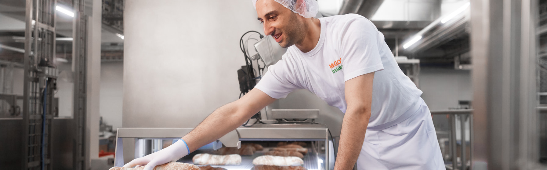 Mann ordnet Brot auf Fliessband Mann ordnet Brot auf Fliessband
